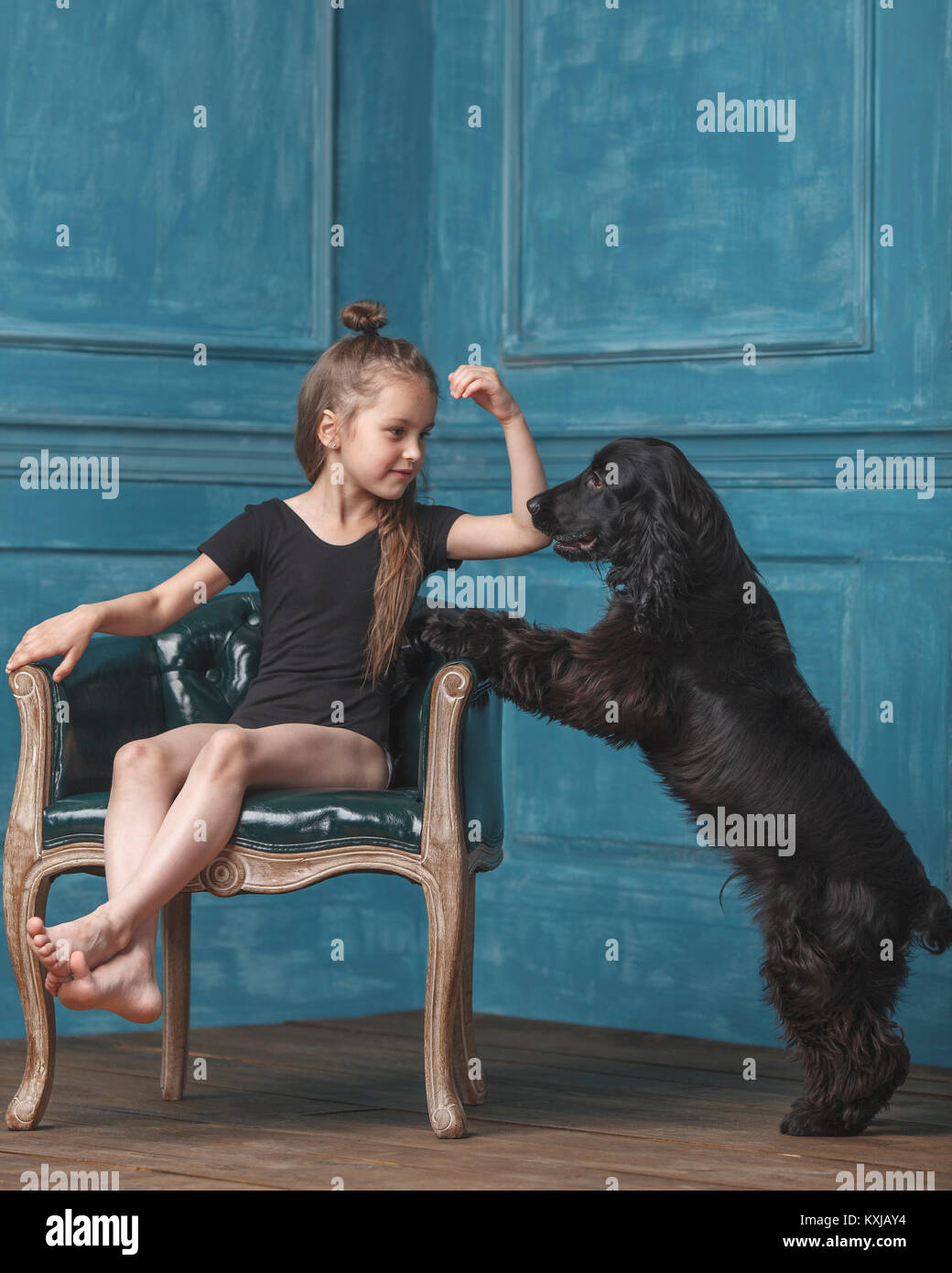 Pleine longueur de fille assise sur une chaise ancienne tout en regardant le chien élever à la maison Banque D'Images