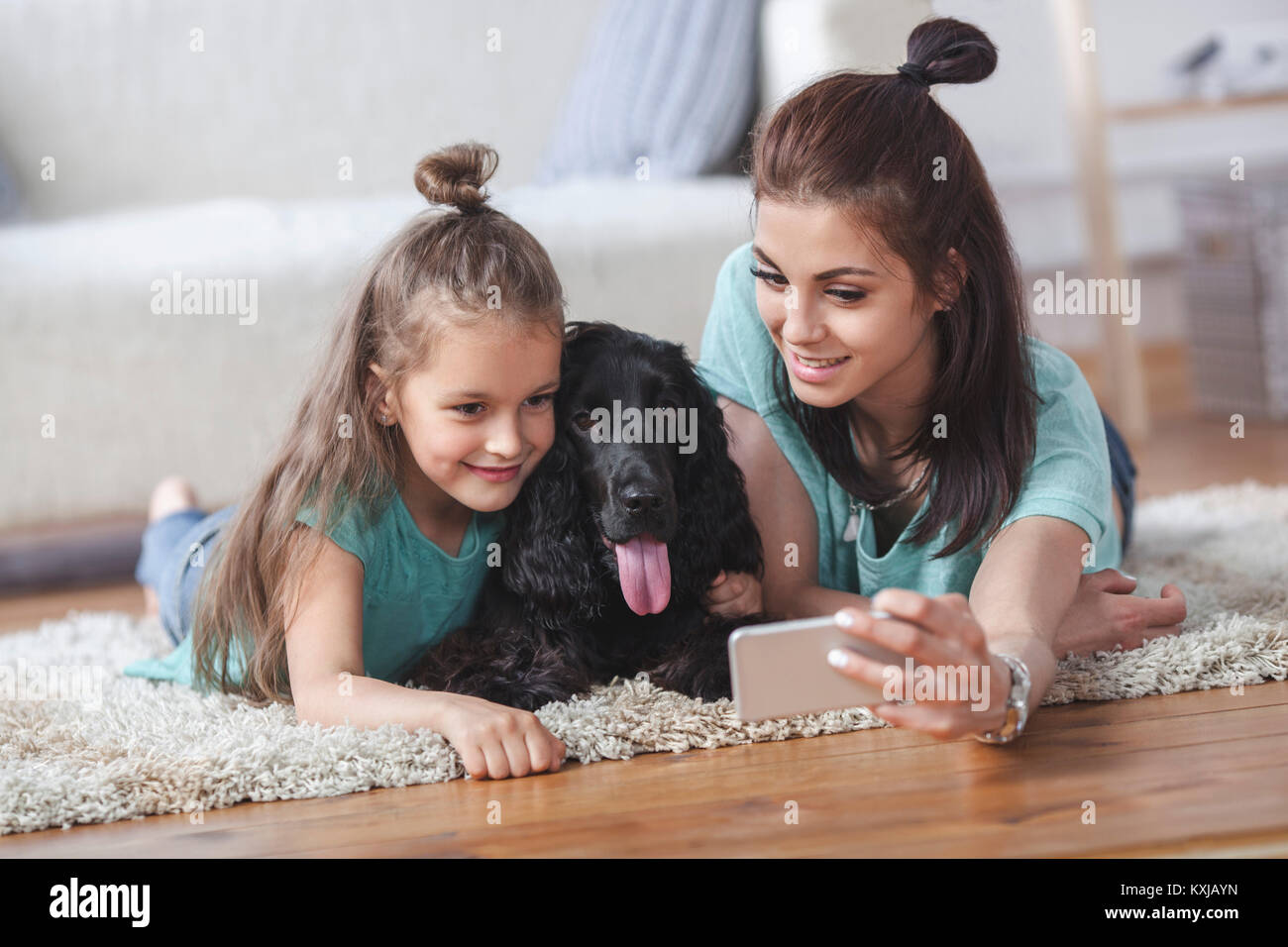 Une jeune femme avec sa fille et son chien prend son selfie en utilisant son smartphone à la maison Banque D'Images