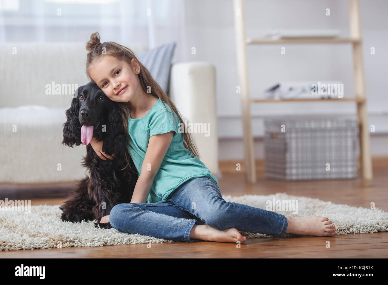 Portrait d'une jolie fille qui embrasse le chien tout en étant assis sur un tapis à la maison Banque D'Images