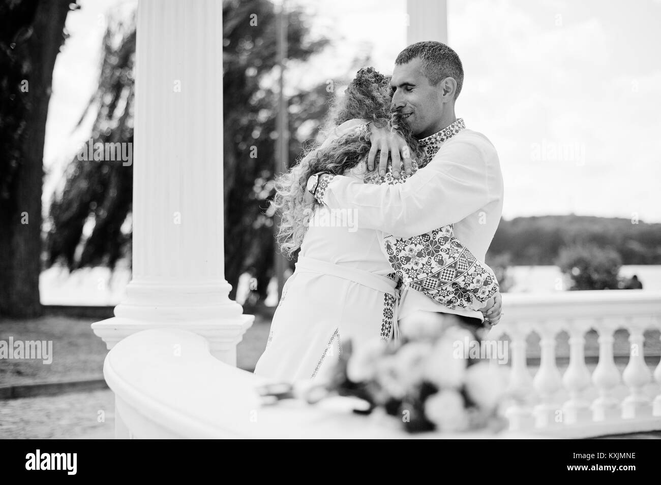 Jeune couple de mariage romantique en vêtements traditionnels ukrainiens hugging in gazebo. Photo en noir et blanc. Banque D'Images