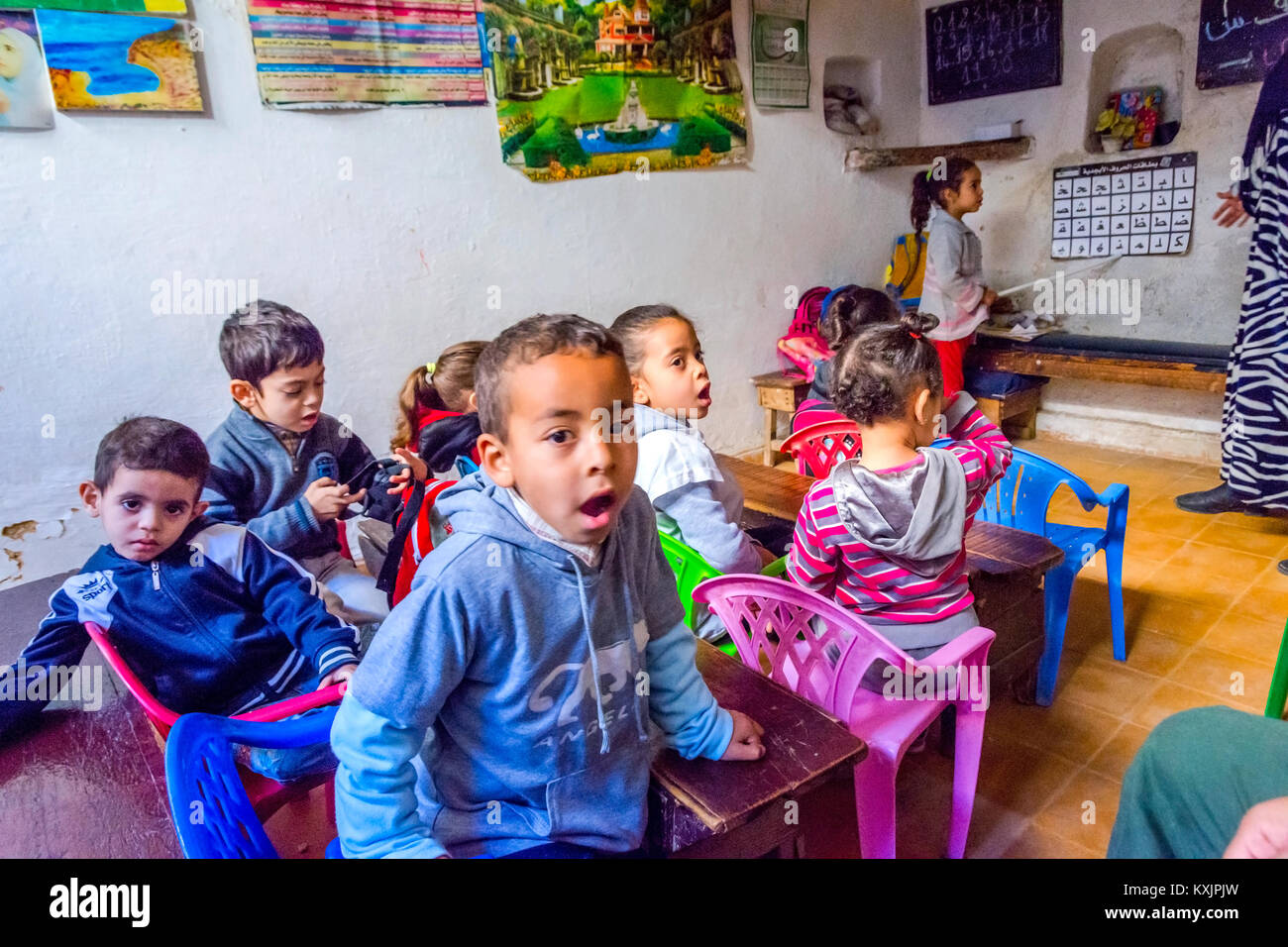 Fes, MAROC - 10 DÉCEMBRE : School girl debout devant la classe et en pointant sur l'alphabet en lettres arabes de l'école locale de Fès. Décembre 2016 Banque D'Images