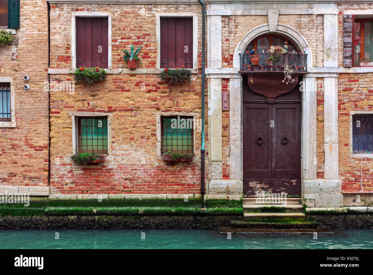Façade de maison en briques anciennes moussus partiellement avec du vintage porte à petit canal à Venise, Italie. Banque D'Images
