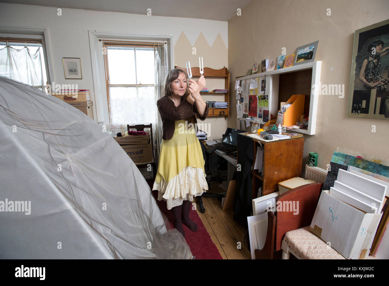 Femme qui souffre du syndrome d'hypersensibilité électromagnétique de l'intolérance qui y est associée (EHS) maintenant la guérison Diapasons et dort à l'intérieur d'une cage de Faraday, UK Banque D'Images