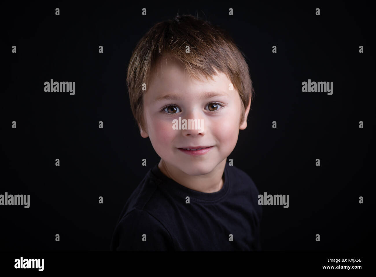 Close-up portrait of a 5 ans garçon à la recherche en appareil photo sur un fond noir Banque D'Images