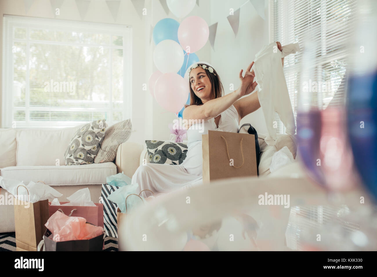 Souriante jeune femme enceinte cadeaux offerts par ses amis. Ouverture féminine présente reçu lors de partie de douche de bébé. Banque D'Images