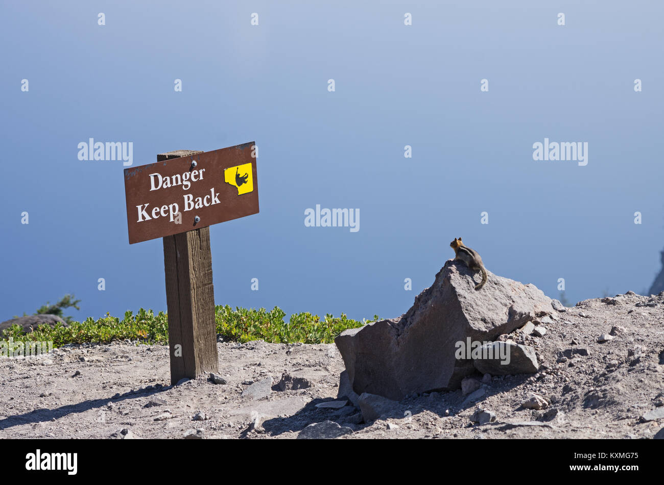 Un tamia à à un danger en gardant le dos signe à un lac de cratère surplombent Banque D'Images