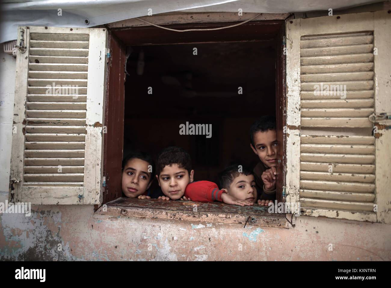 (180111) -- Gaza, 11 janvier 2018 (Xinhua) -- Les membres de la famille Abu amer de la Palestine vivant dans des conditions difficiles, ni de leur fenêtre de taudis, dans le camp de réfugiés de Nuseirat, centre de la bande de Gaza, le 11 janvier 2018. Rapports internationaux et israéliens a déclaré que les intentions des Etats-Unis de geler ou d'en retarder le fonds financier pour l'Organisation des Nations Unies pour les activités de secours et de travaux pour les réfugiés de Palestine dans l'Extrême-Orient (UNRWA) et arrêter l'aide aux Palestiniens jusqu'à leur retour à la table des négociations avec Israël. L'Office, qui fournit de l'aide dans l'éducation, la santé et l'alimentation de quelque cinq millions d'inscrits Banque D'Images