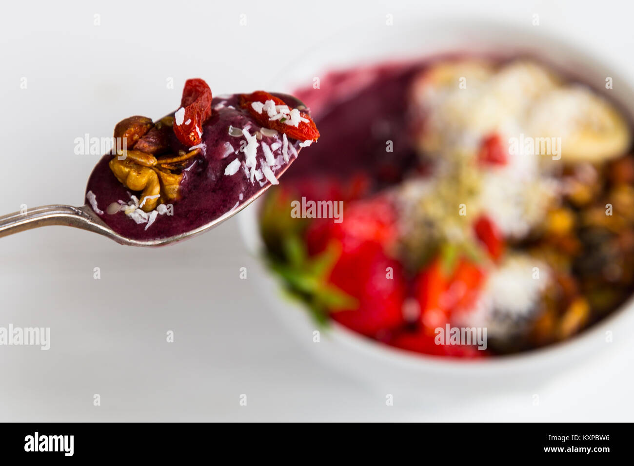 Cuillère de petit-déjeuner d'Acai acai - Bol de garnitures de purée de banane, fraise, granola et les graines. Banque D'Images
