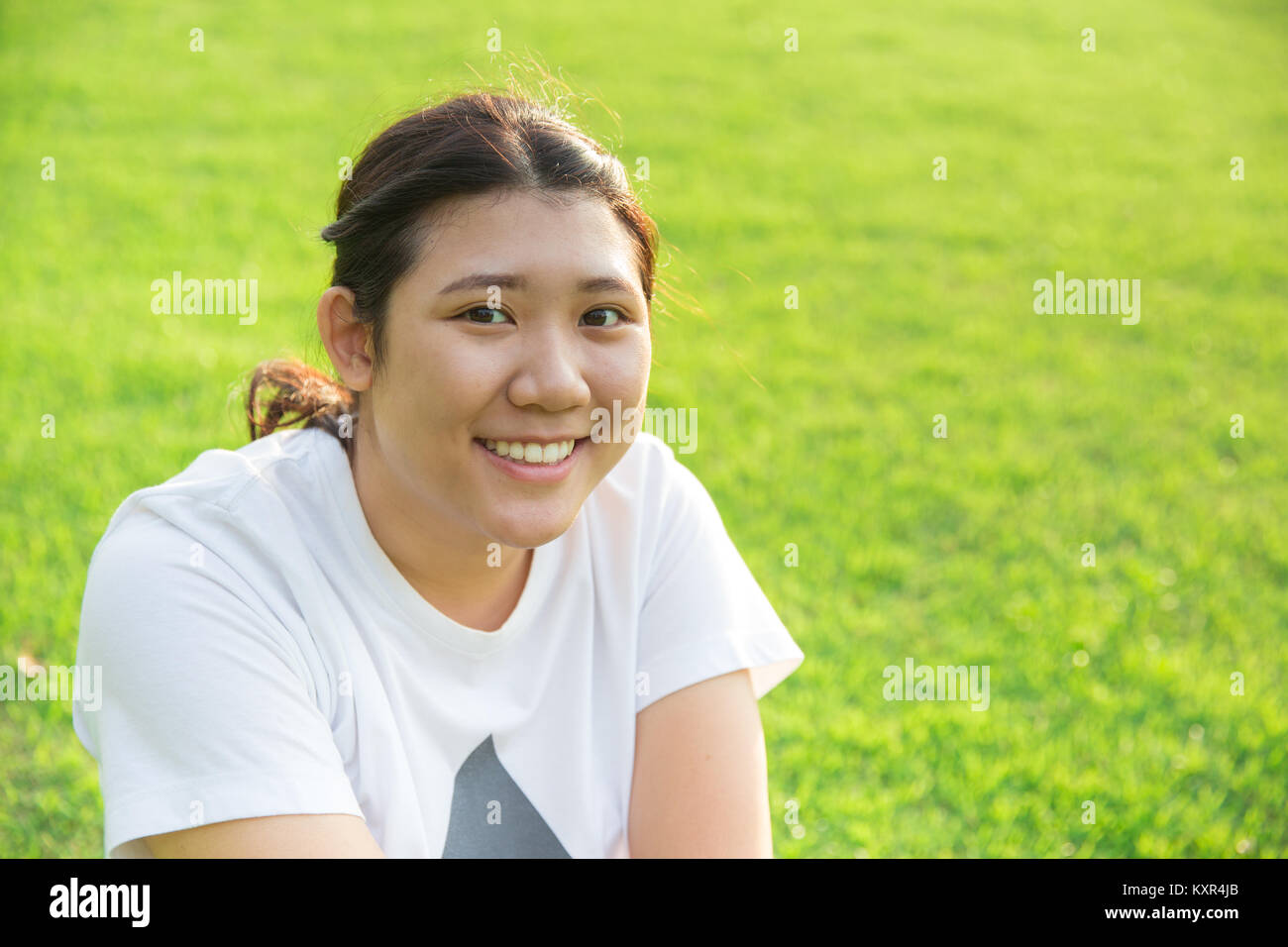 Cute asian teen sourire avec la bonne santé des dents sur fond d'herbe verte Banque D'Images
