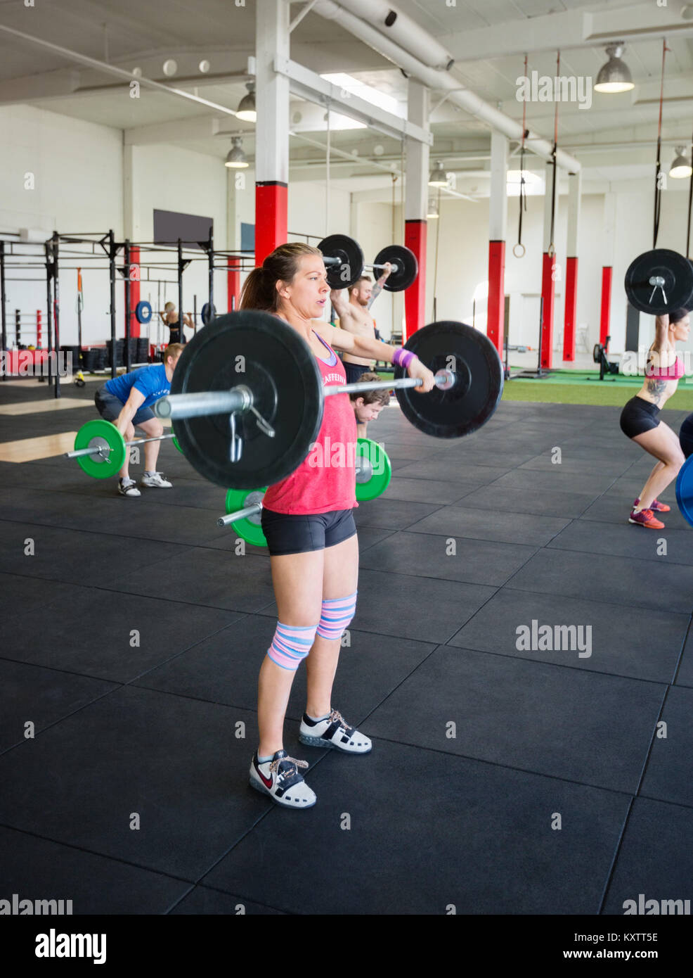 Toute la longueur du jeune femme déterminée d'haltères de levage in gym Banque D'Images