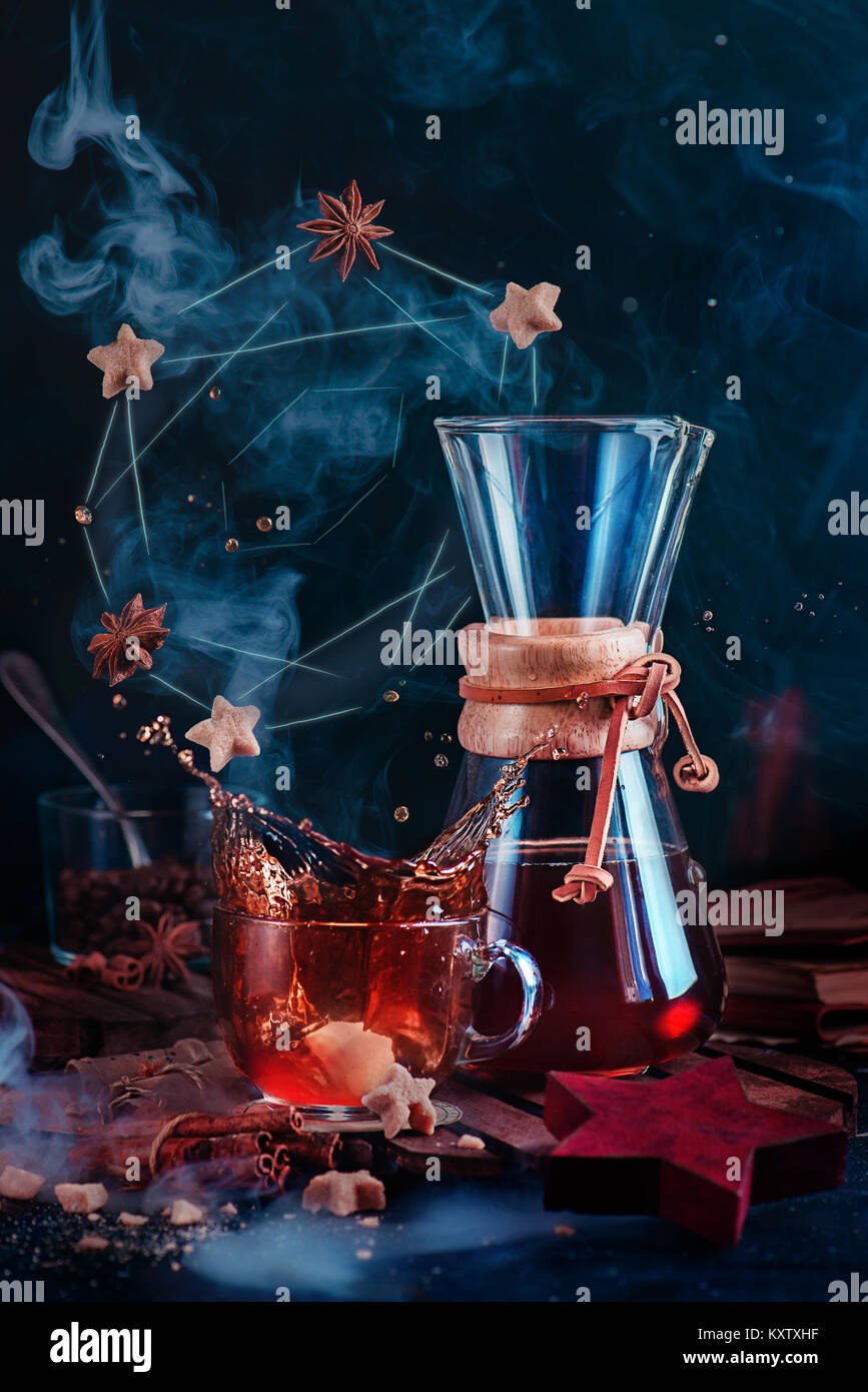 Tasse à café en verre avec un splash dynamique et croissant avec la vapeur d'un beigne constellation. Cafetière en forme de sablier sur un fond sombre avec copie espace. Banque D'Images