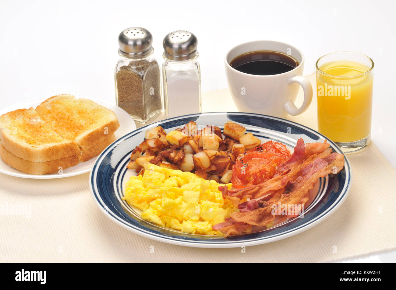 American blue plate spéciale petit-déjeuner avec des œufs brouillés, paillasson de pommes de terre, lardons, tomates grillées, beurrées toast blanc, verre de jus d'orange Banque D'Images