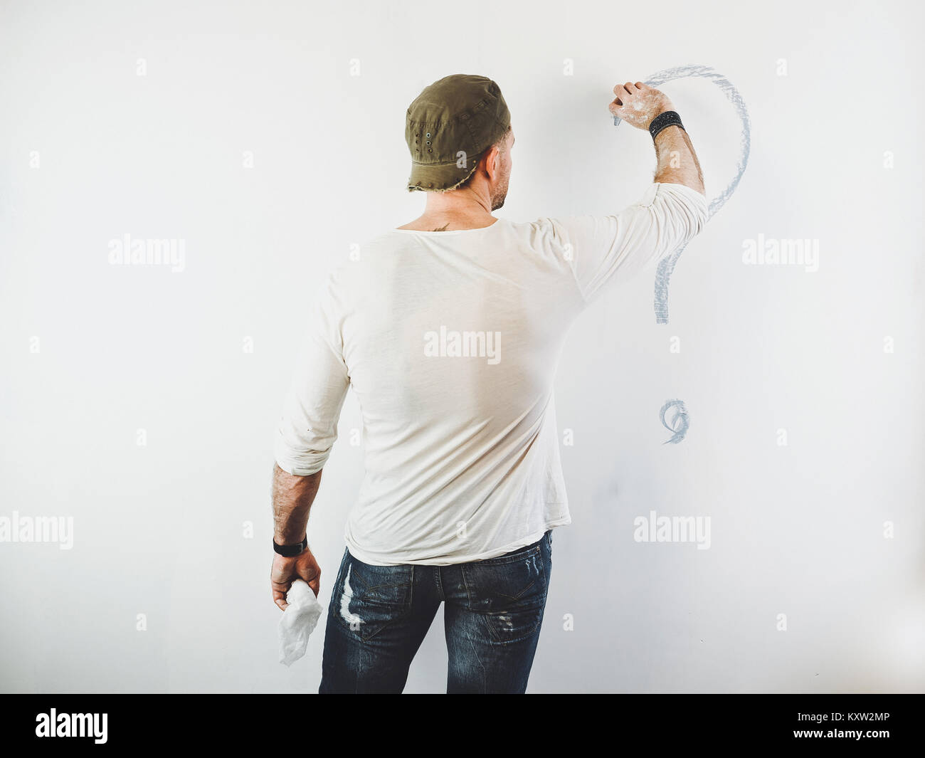 Guy l'effacement d'un point d'interrogation sur un mur blanc à l'aide d'un rouleau Banque D'Images