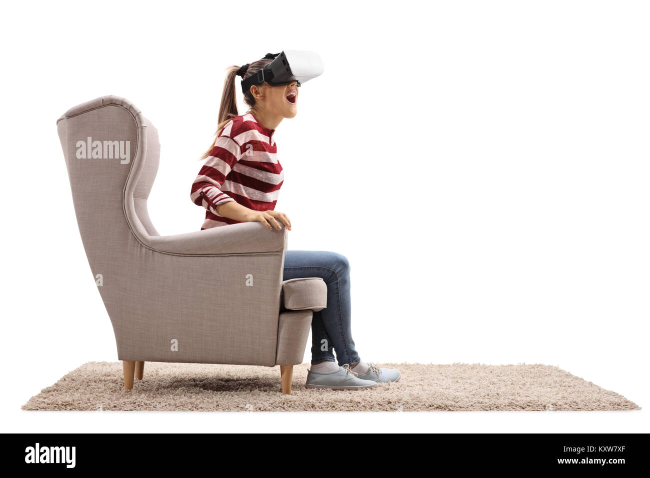 Surpris jeune femme assise dans un fauteuil à l'aide d'un casque de réalité virtuelle isolé sur fond blanc Banque D'Images