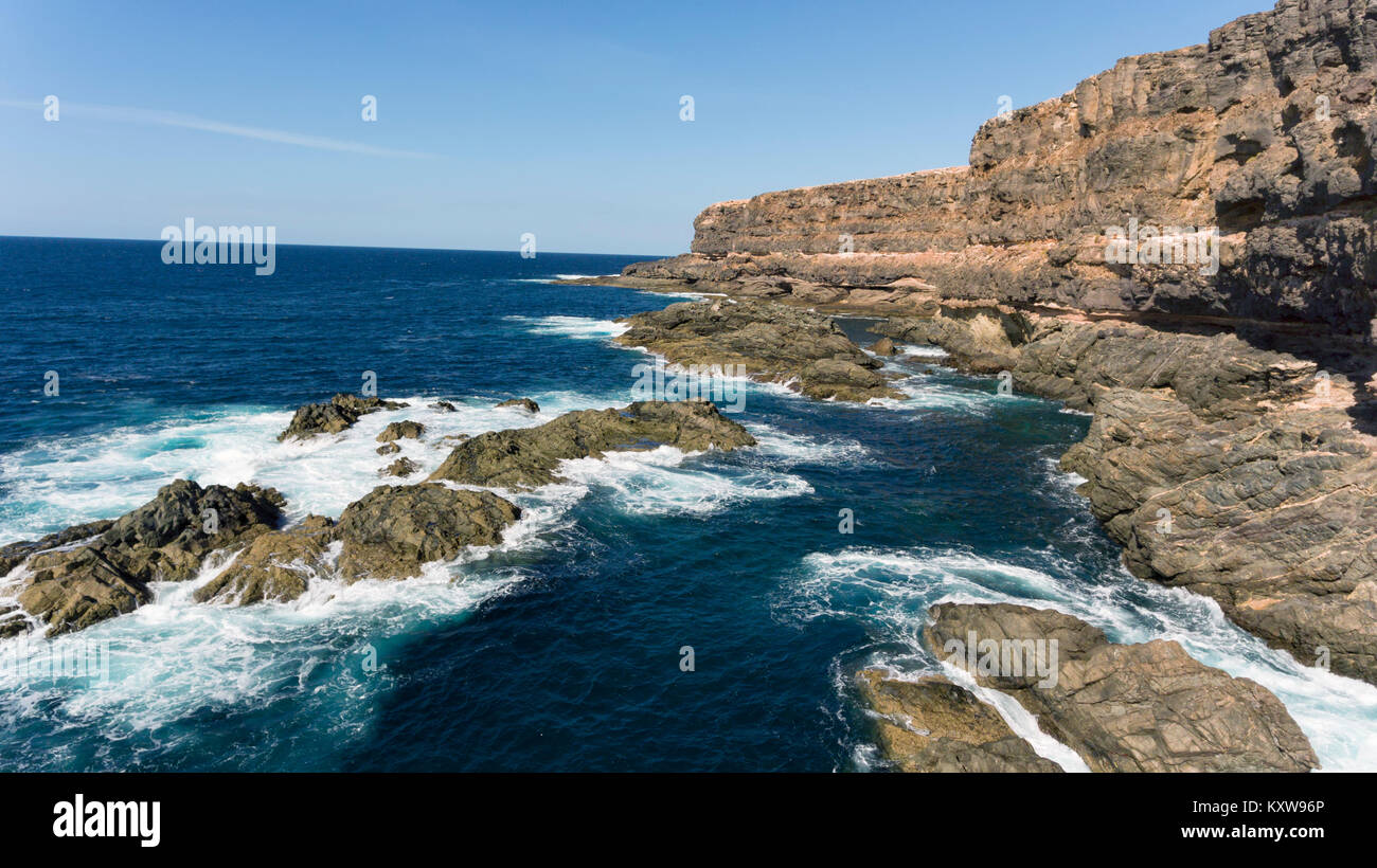 Mer agitée avec des vagues sur les rochers en granite abruptes, côte de l'océan Atlantique, Fuerteventura, Îles Canaries, Espagne . Banque D'Images