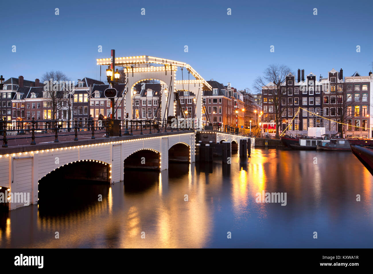 Les Pays-Bas, Amsterdam, Maisons du xviie siècle à rivière appelée Amstel. Unesco World Heritage Site. Pont maigre en arrière-plan. Le crépuscule. Banque D'Images