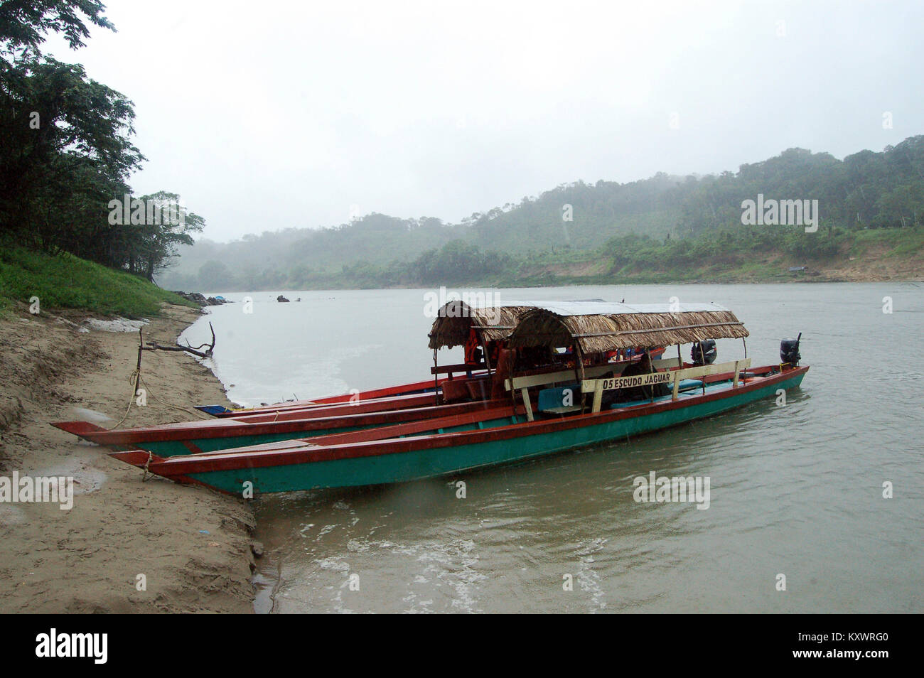 Vue d'un fleuve Usumacinta pluvieux et brumeux, frontière naturelle entre le Mexique et le Guatemala, à partir de la partie mexicaine. Un canot en bois attend par la rive. Banque D'Images