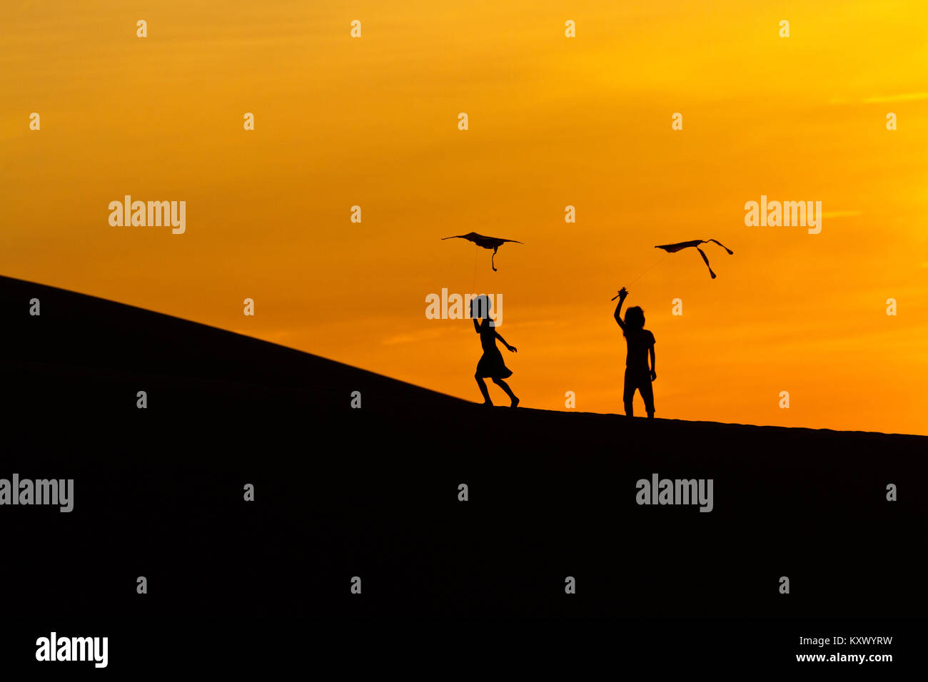Tôt le matin au lever du soleil. Enfants jouant avec des cerfs-volants dans les dunes de sable près de Phan Rang, le centre du Vietnam Banque D'Images