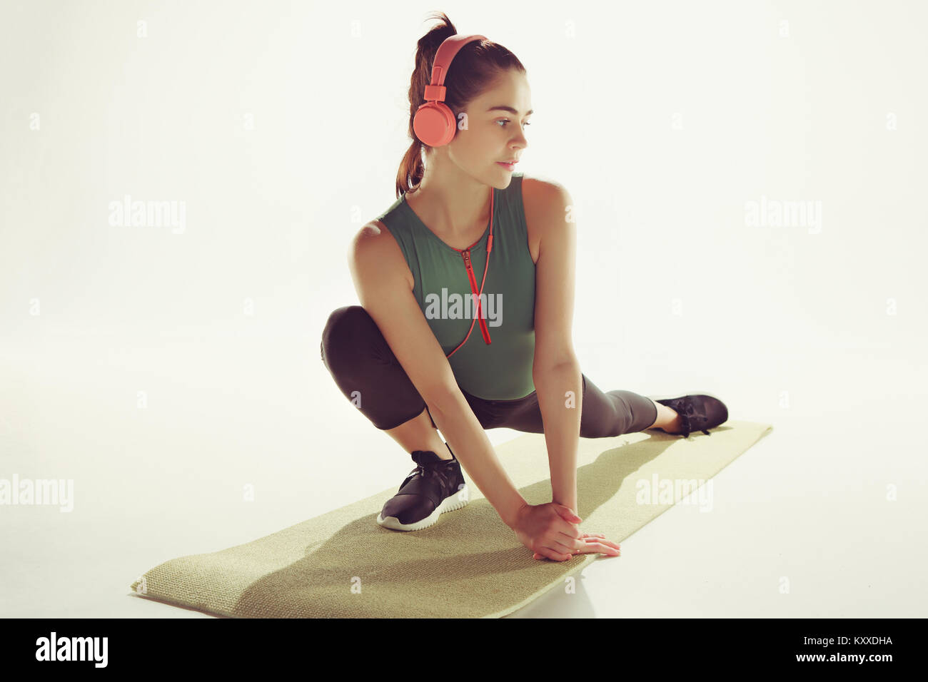 Vue de face d'une jeune femme qui s'étend en gymnastique du corps. Banque D'Images