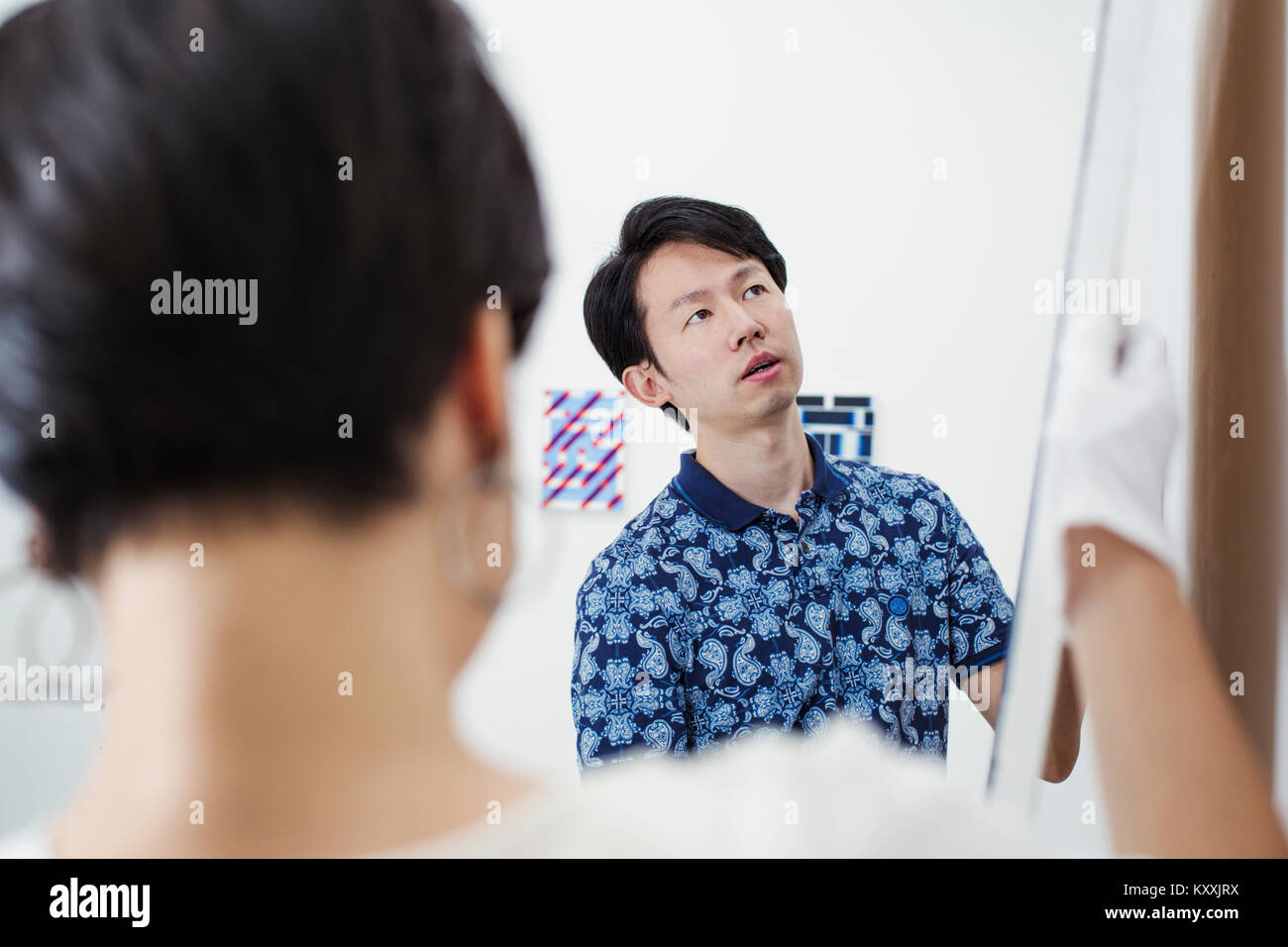 L'homme en chemise bleue et woman wearing white shirt hanging peinture moderne sur mur blanc dans l'art gallery. Banque D'Images