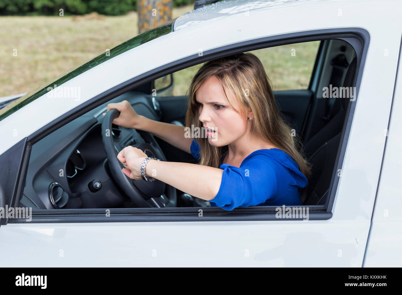 Jeune femme expressive conduisant une voiture et à regarder à être en retard Banque D'Images