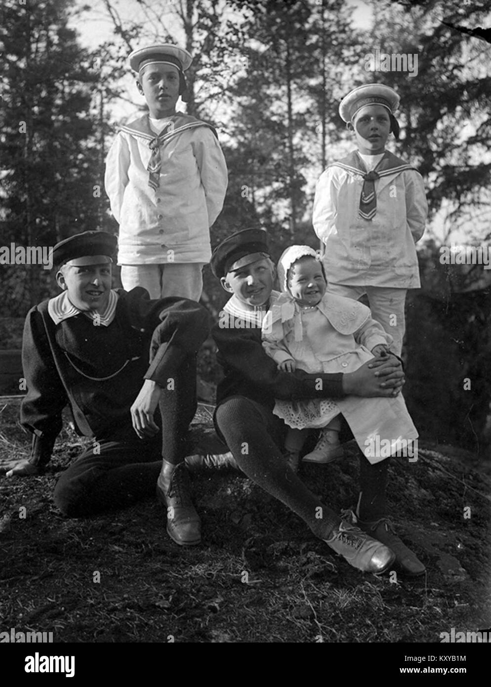 Une photographie historique de Suède montrant quatre garçons vêtus de costumes de marin, dont un tenant un bébé, illustrant la mode des enfants du début du XXe siècle et la vie de famille. Banque D'Images