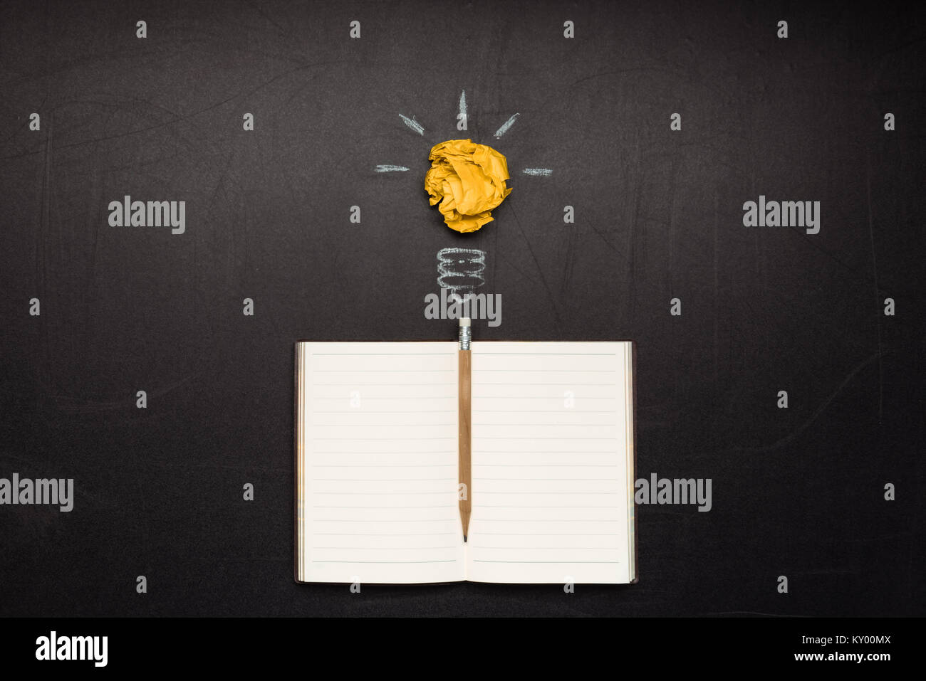 Symbole de l'ampoule et blank notebook avec crayon sur tableau noir Banque D'Images