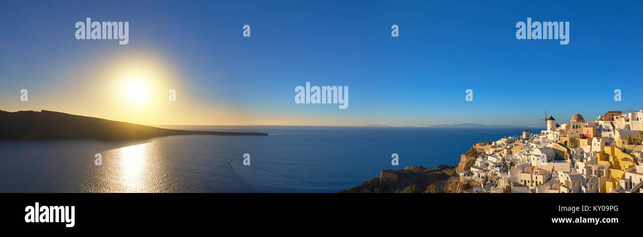Coucher de soleil sur l'île de Santorin en Grèce. L'église traditionnelle, les appartements et les moulins à vent à Oia village sur un coucher de soleil, photo panoramique. Banque D'Images