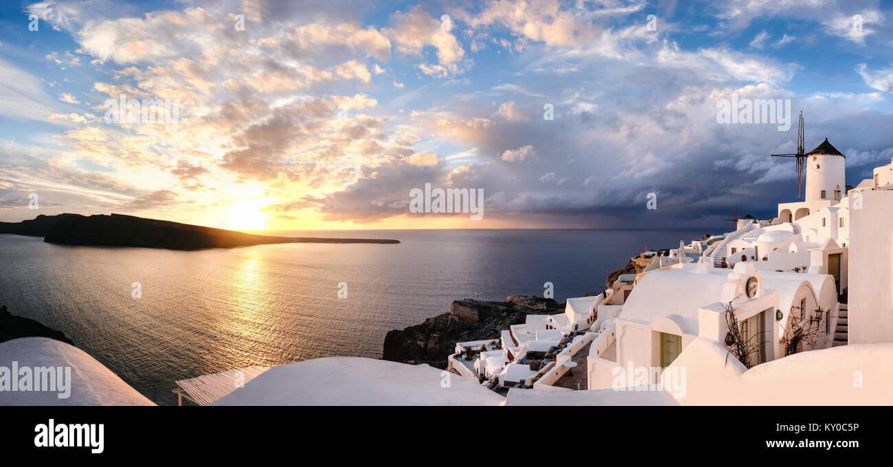 Coucher de soleil sur l'île de Santorin en Grèce. L'église traditionnelle, les appartements et les moulins à vent à Oia village sur un coucher de soleil, photo panoramique. Banque D'Images