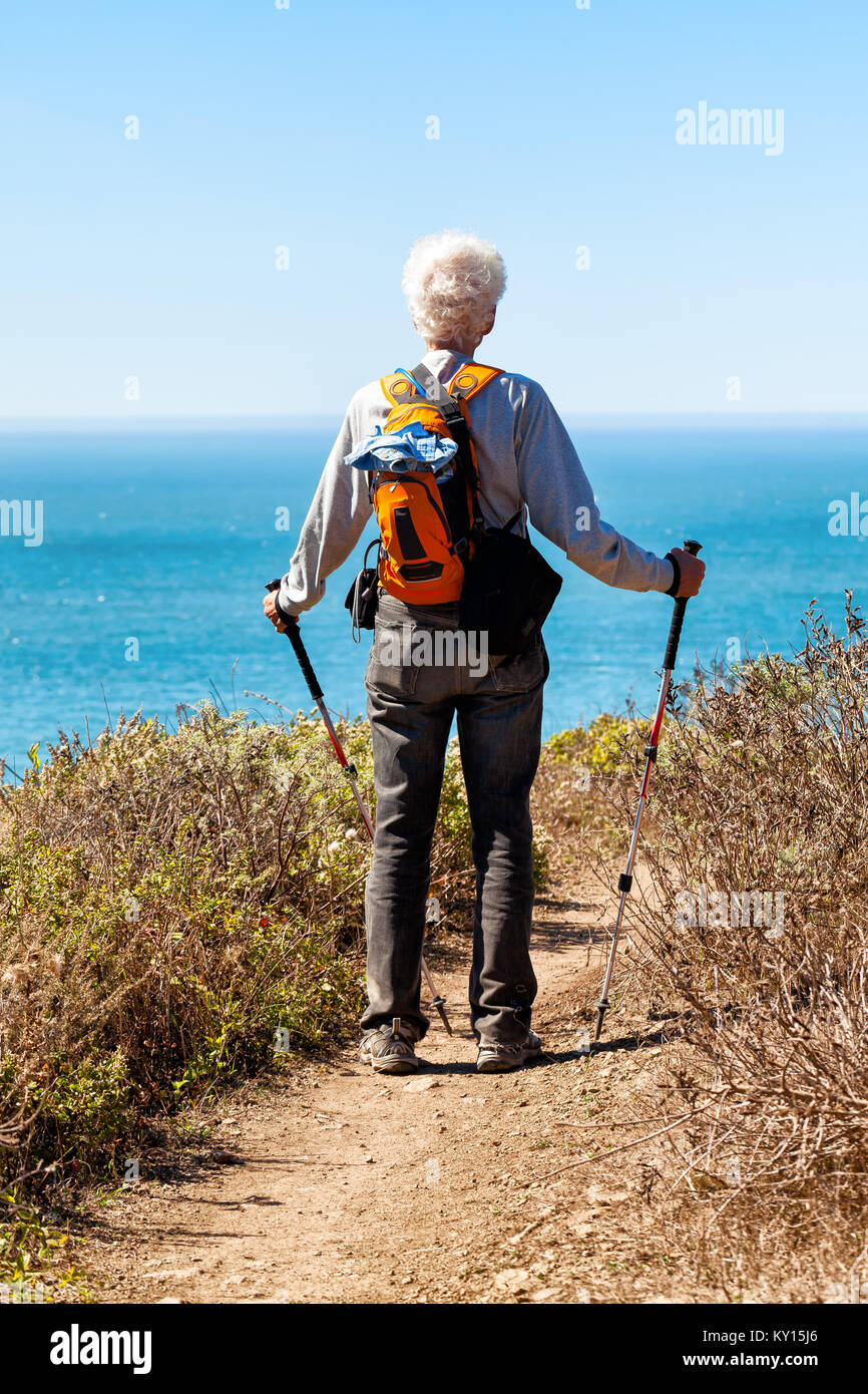 Senior actif sur un sentier de randonnée s'arrête pour regarder une vue sur l'océan Pacifique, à 30 miles au nord de San Francisco. Concept positif pour le vieillissement en santé. Banque D'Images
