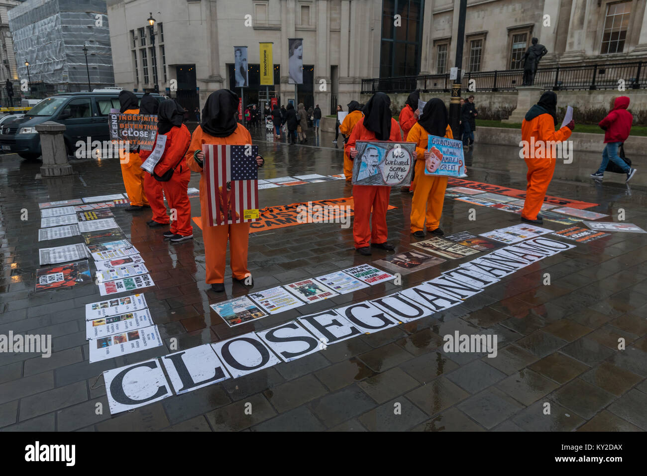 Janvier 11, 2018 - Londres, Royaume-Uni. 11 janvier 2018. Les combinaisons de saut orange et noir hoods debout dans un square à Trafalgar Square marquant 16 ans de la détention illégale et la torture au camp de Guantanamo Bay. Les noms des 41 détenus restants ont été lus, de nombreux détenus indéfiniment sans accusation ni procès, presque tous ceux qui ont été vendus aux Etats-Unis par des milices afghanes et les primes en espèces pour les militaires pakistanais avec aucune preuve réelle d'implication terroriste, mais dont la torture dans des prisons secrètes de la CIA à travers le monde avant l'arrivée à Guantanamo comme tout comme tout au long de leur détention n'y fait Banque D'Images