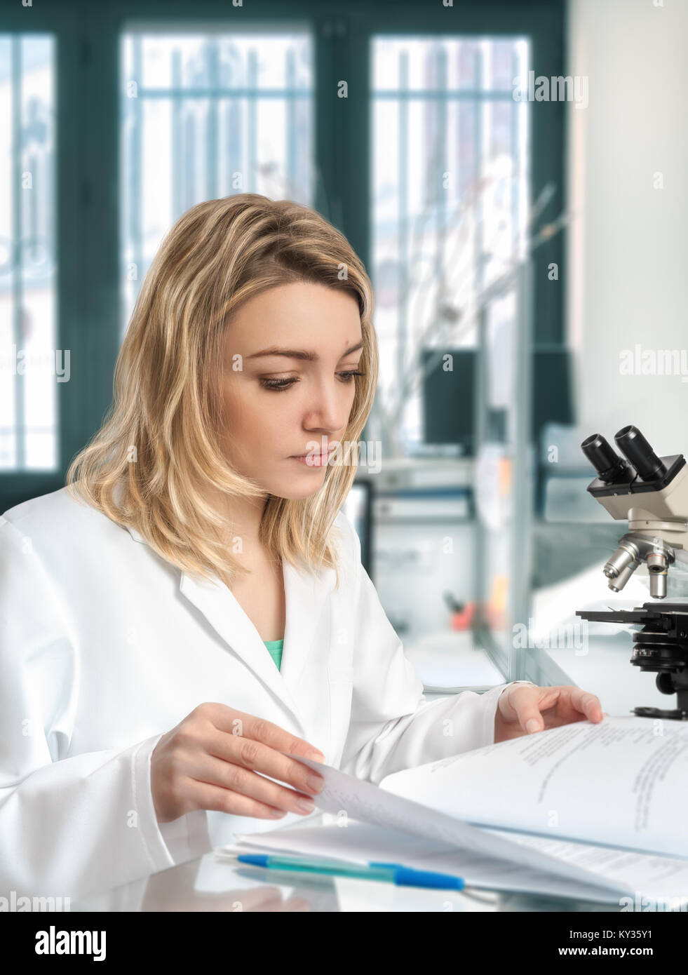 Jeune femme scientifique dans son laboratoire vérifie son journal de laboratoire Banque D'Images