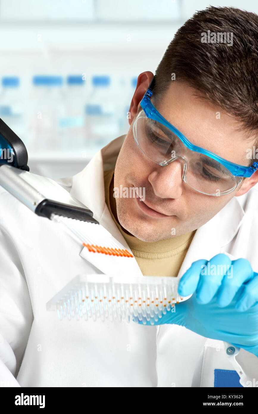 Jeune biologiste définit le séquençage d'ADN réaction avec pipette multicanaux Banque D'Images