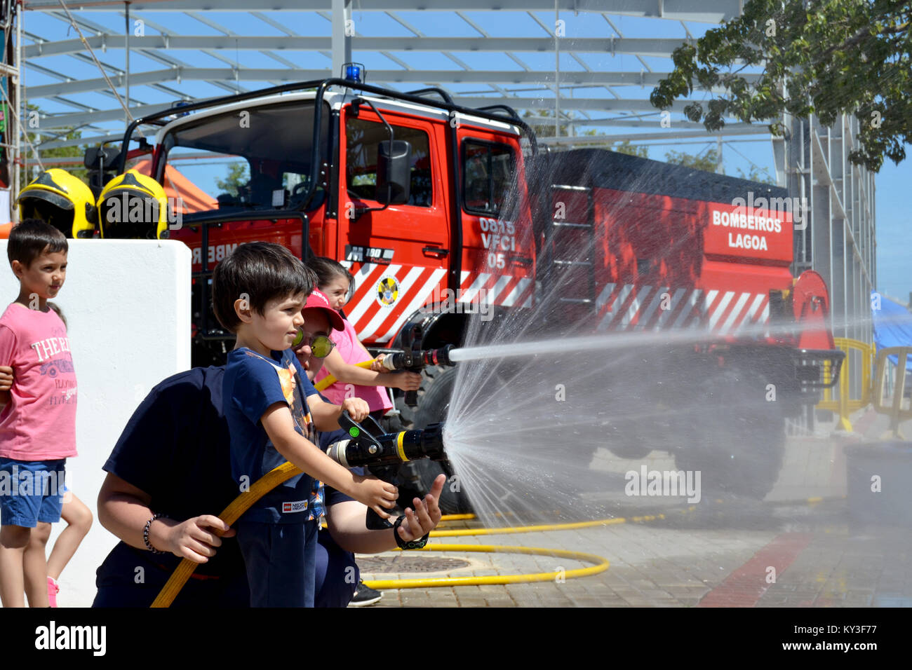 Portugal, Algarve, Lagoa, vers 04.06.2017 Les enfants à apprendre comment être les pompiers à l'aide de tuyaux d'incendie lors d'une foire internationale locale au Portugal. Banque D'Images