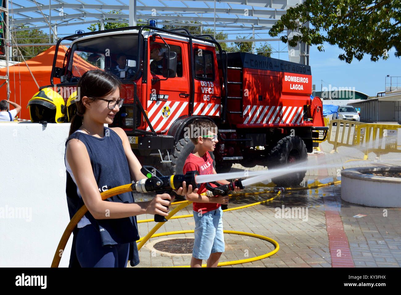 Portugal, Algarve, Lagoa, vers 04.06.2017 Les enfants à apprendre comment être les pompiers à l'aide de tuyaux d'incendie lors d'une foire internationale locale au Portugal. Banque D'Images