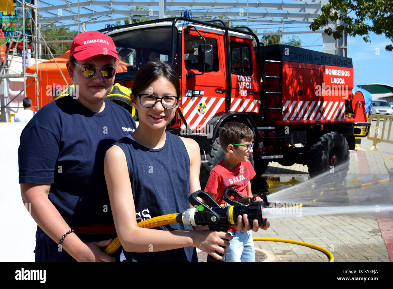 Portugal, Algarve, Lagoa, vers 04.06.2017 Les enfants à apprendre comment être les pompiers à l'aide de tuyaux d'incendie lors d'une foire internationale locale au Portugal. Banque D'Images