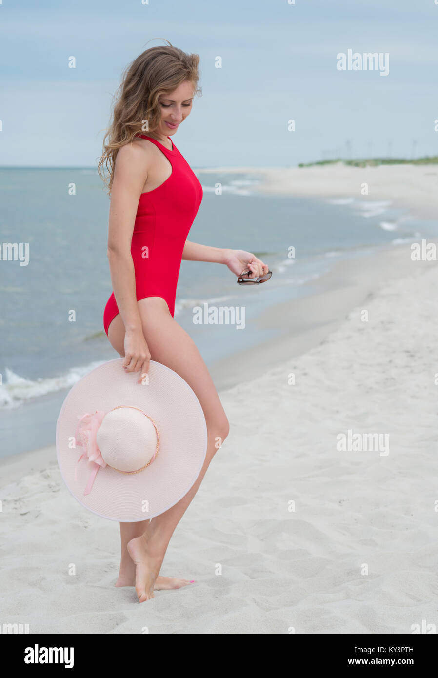 Une Femme En Maillot De Bain Rouge Se Tient Sur Une Plage.