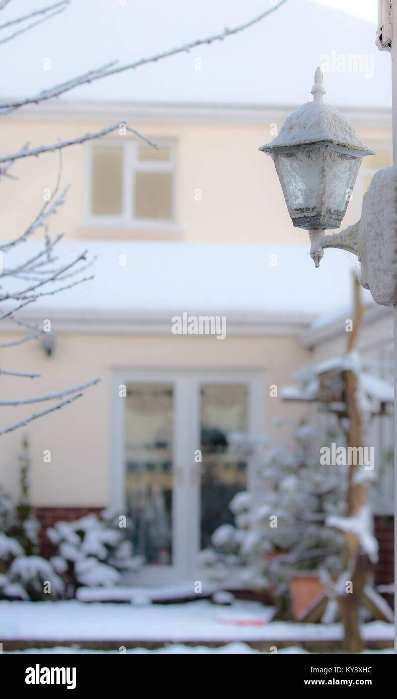 Un coup d'hiver lumineux de la capture d'un style traditionnel coach extérieur lanterne couverte de neige. Soft-focus contexte montre bien couverte de neige et jardin. Banque D'Images