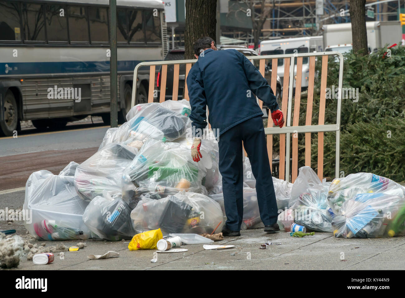 Un ouvrier d'entretien porte sur son pieux du bâtiment de déchets en attente de pick-up à New York, le Jeudi, Janvier 11, 2017. Comme la neige fond de notre récente tempête et des températures glaciales le ministère de l'assainissement commence à reprendre l'ensemble de la montagne d'ordures, aggravé par les arbres de Noël et de l'utilisation des déchets domestiques de cadeaux de Noël. (© Richard B. Levine) Banque D'Images