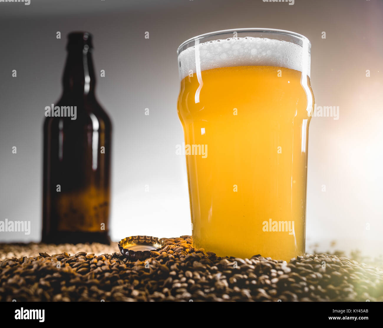 Bière Blonde de Homebrew sur Grain Pilsner Heap et bouteille vide en arrière-plan Banque D'Images