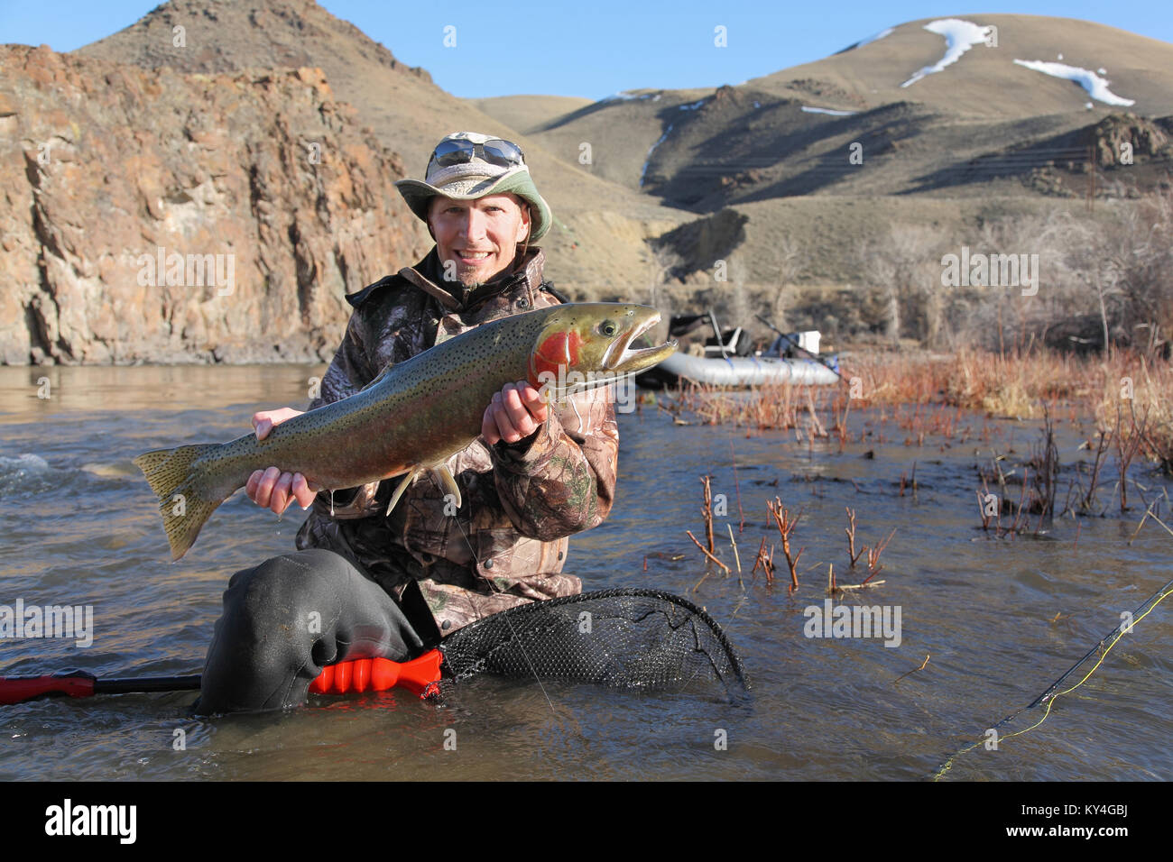 pêcheur adulte tenant une grosse truite arc-en-ciel sur un grand rivière Banque D'Images