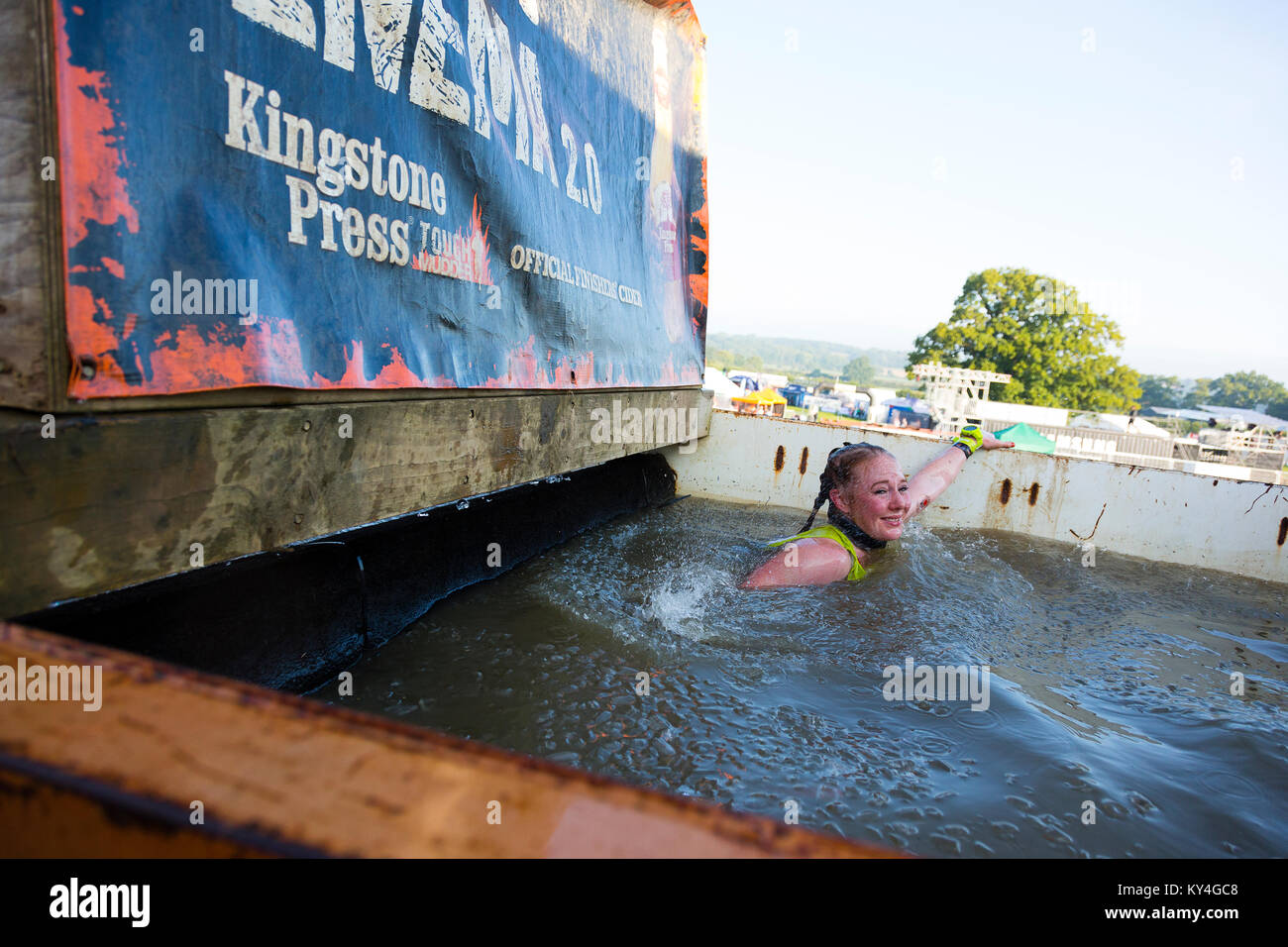 Sussex, UK. Une jeune femme grimaces comme elle nage à travers un bassin d'eau glacée pendant une dure Mudder course à obstacles. Banque D'Images