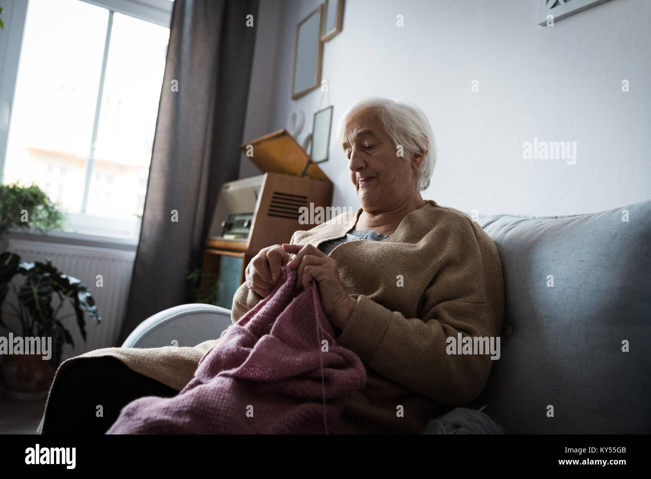 Senior woman knitting une laine dans la salle de séjour Banque D'Images