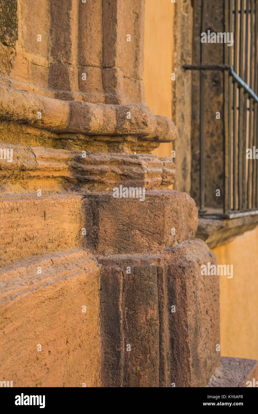 Isolés, gros plan d'une partie d'un massif de bâtiment en pierre, avec ses détails architecturaux, et la tige de la fenêtre fer de bars, dans San Miguel de Allende, Mexique Banque D'Images