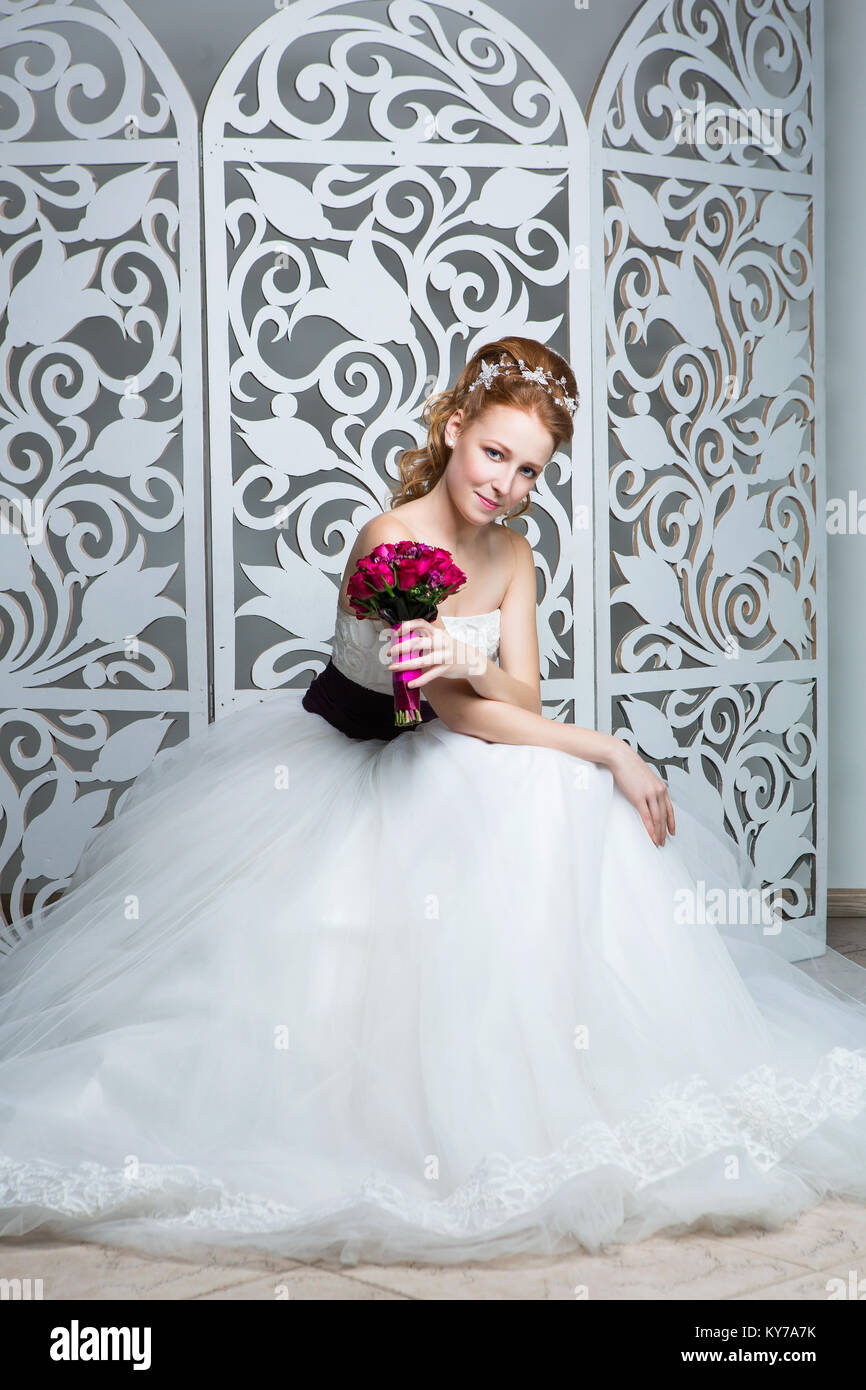 Belle jeune femme cheveux rouge en robe de mariage blanc avec large ceinture pourpre sombre. mariée avec fashion hairstyle. studio shot. Banque D'Images