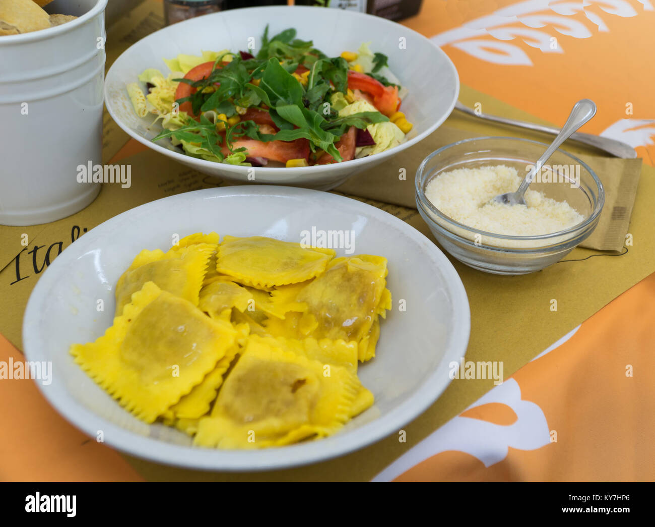 Ravioli farci avec de la citrouille (ravioli di Zucca) servi sur plaque blanche avec salade de style italien et le parmesan râpé dans un restaurant italien. Banque D'Images