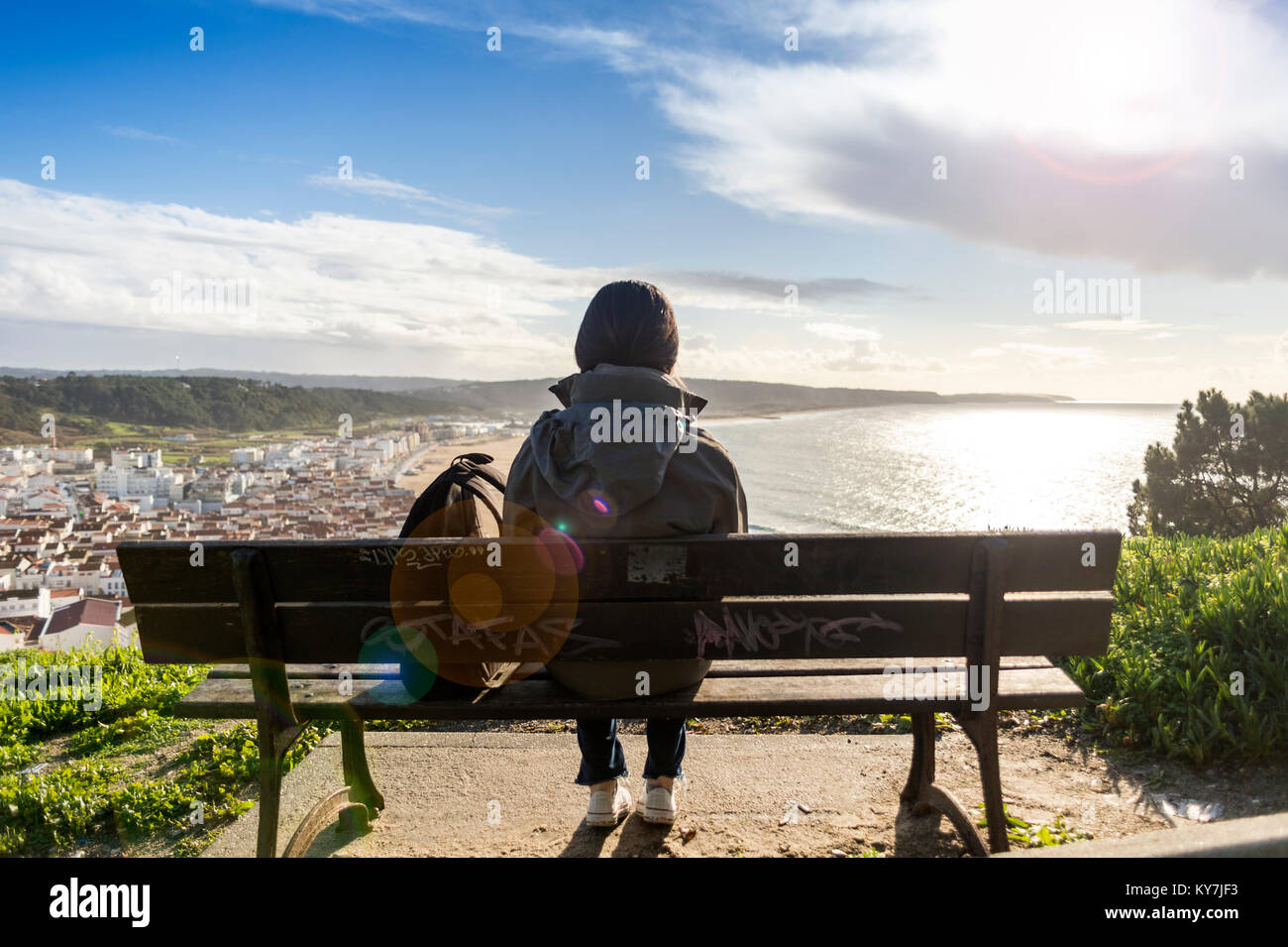 Femme assise sur un banc, profitant de la vue sur la côte et la ville de Leiria au Portugal. Banque D'Images