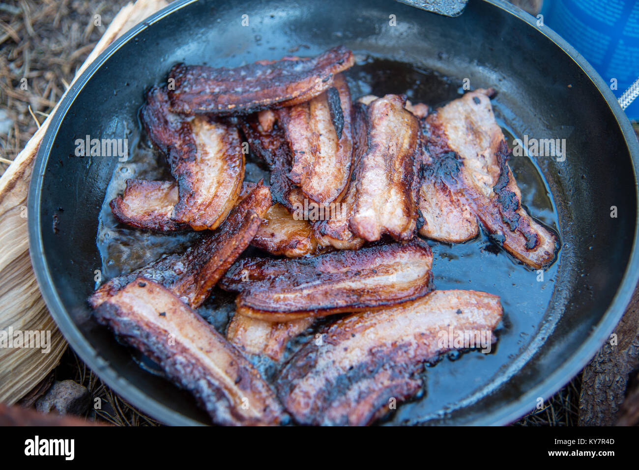 Faire frire le bacon dans une casserole sur un feu ouvert Banque D'Images