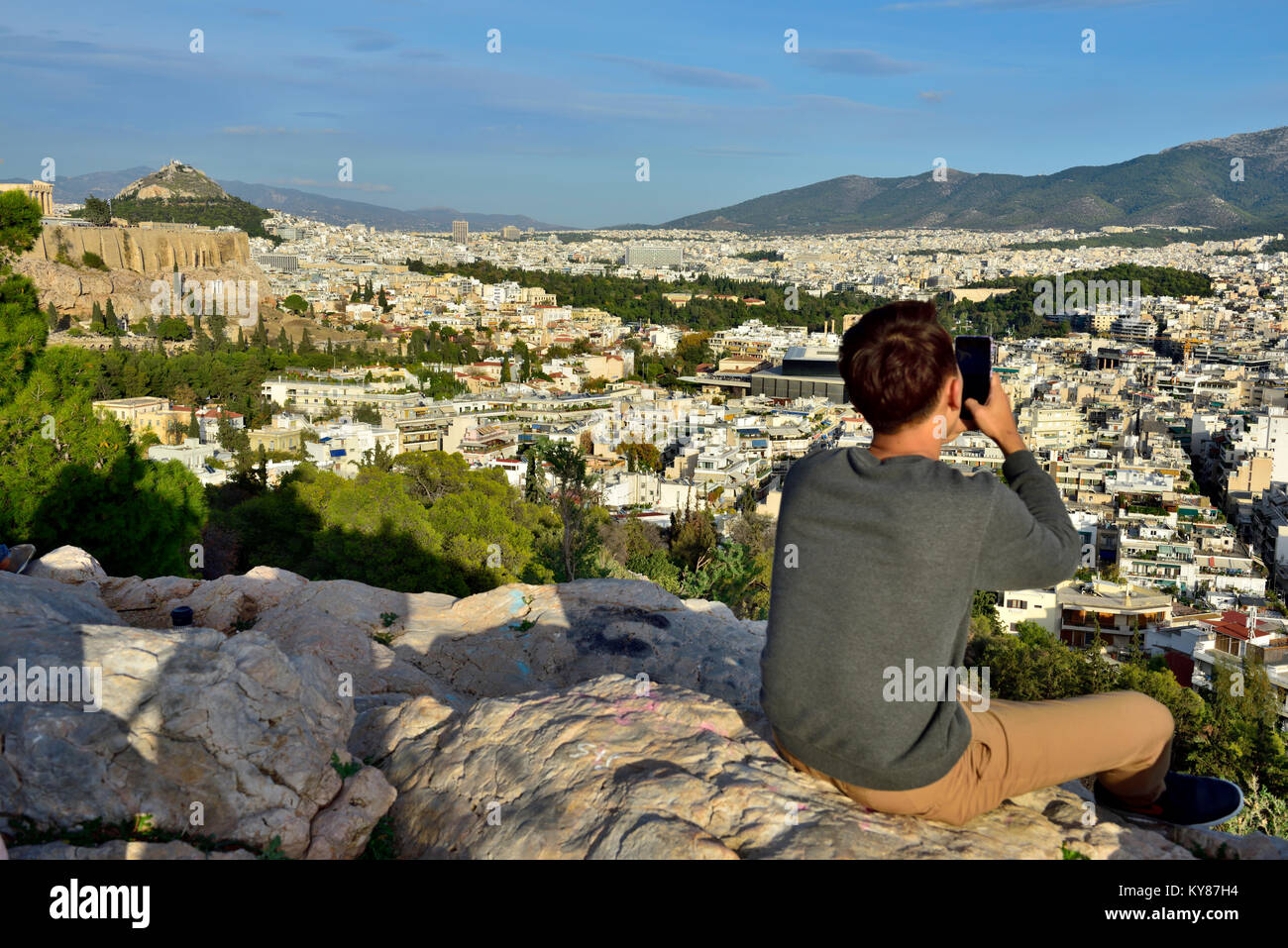 Les jeunes hommes sur le haut de la colline Filopappou (colline des Muses) avec téléphone mobile pour prendre des photos et profiter de la vue sur la ville d'Athènes Banque D'Images