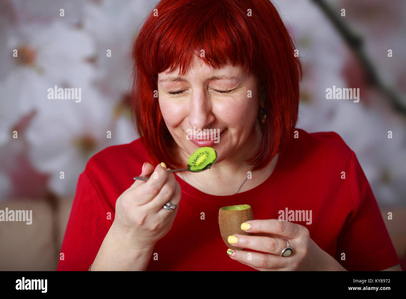 Glamorous young woman eating kiwi et loucher du plaisir. Quel plaisir de manger ce juteux, fruits mûrs et sains. Banque D'Images
